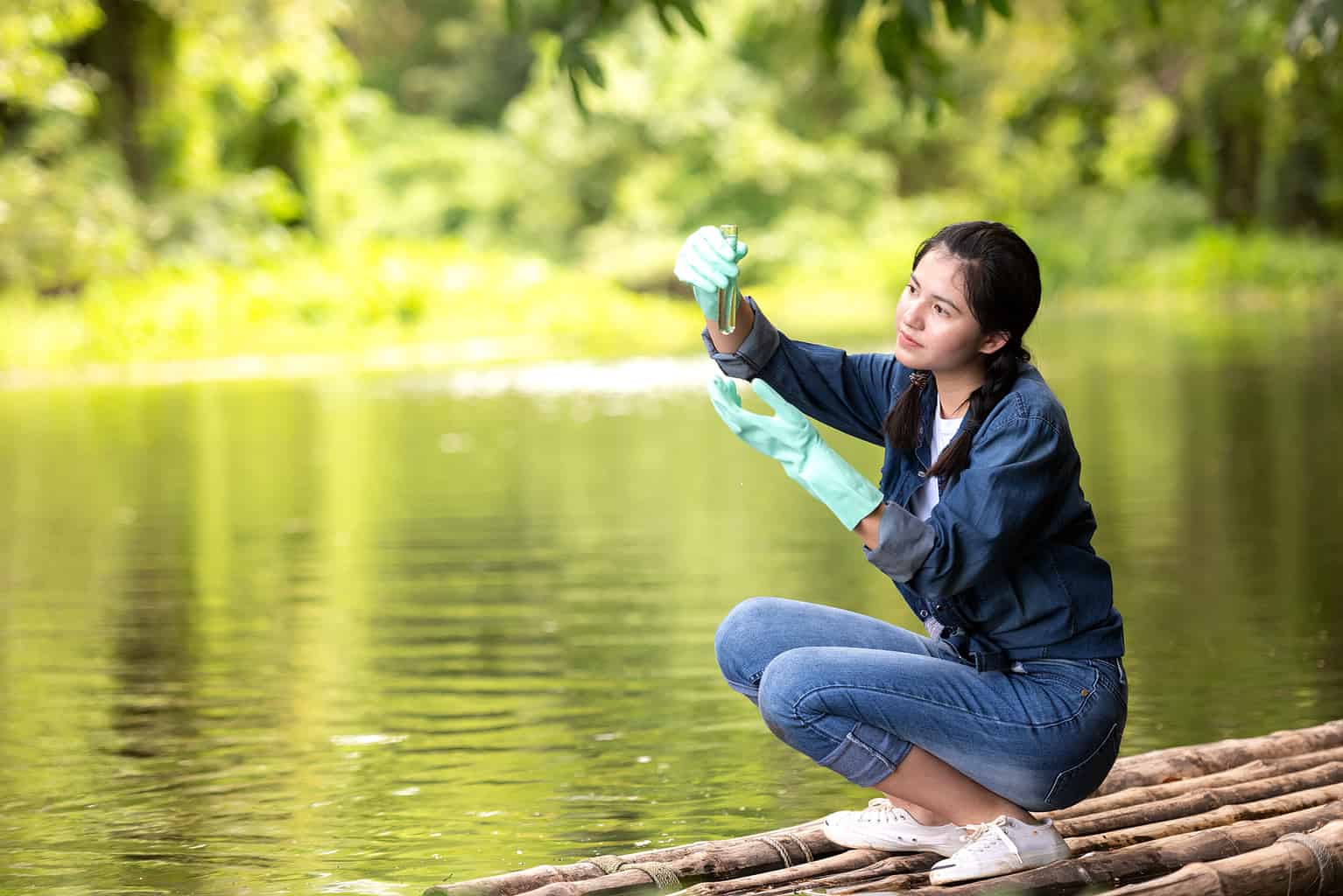 Asian Student Biology Taking And Testing Sample Of Natural River