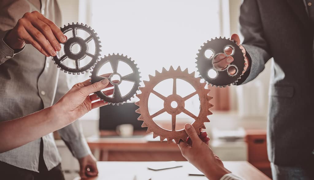 Group Of People Working In The Office While Putting Together Cog
